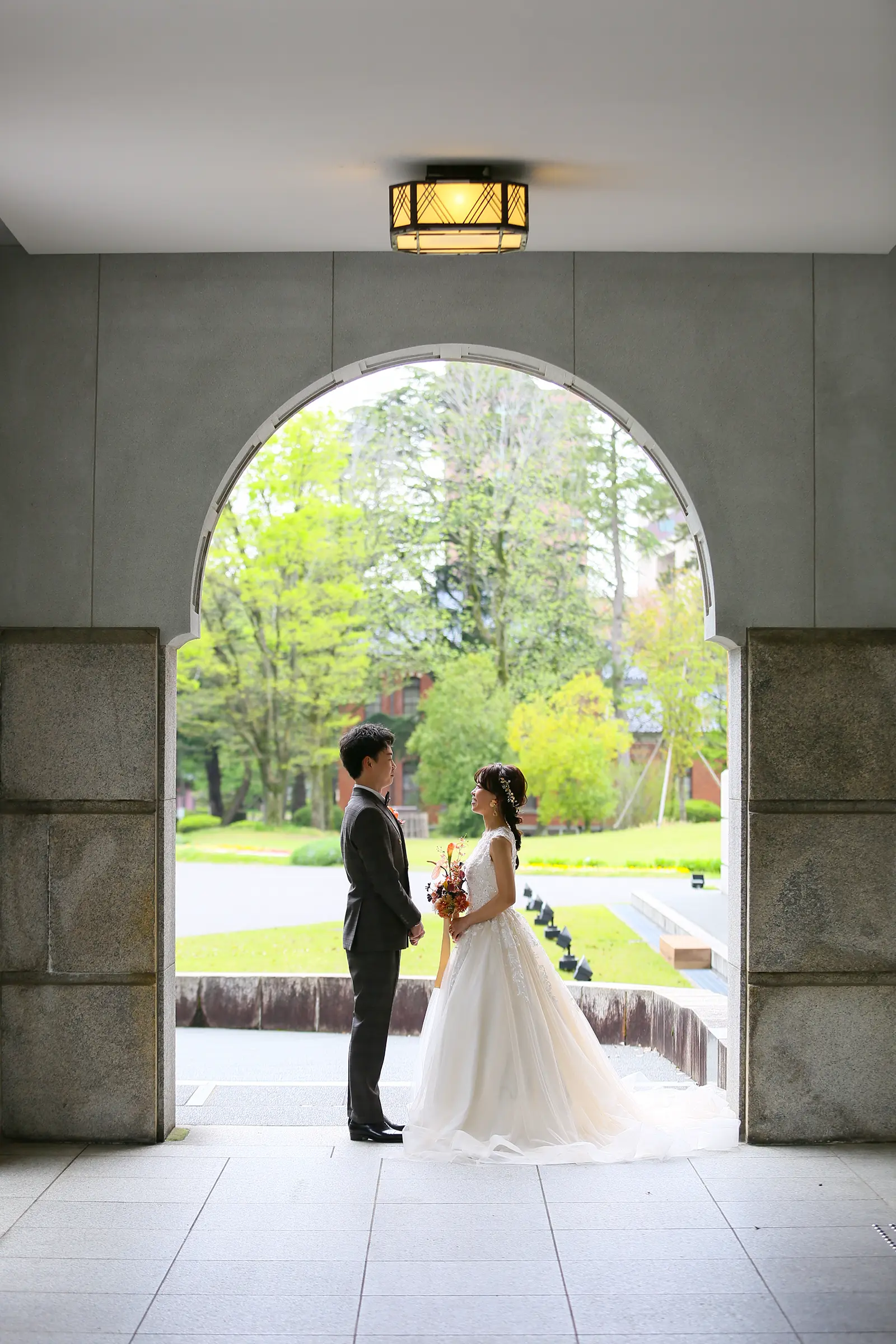 しいのき迎賓館のアーチ入口でウェディングドレス姿の新郎新婦が向かい合う写真