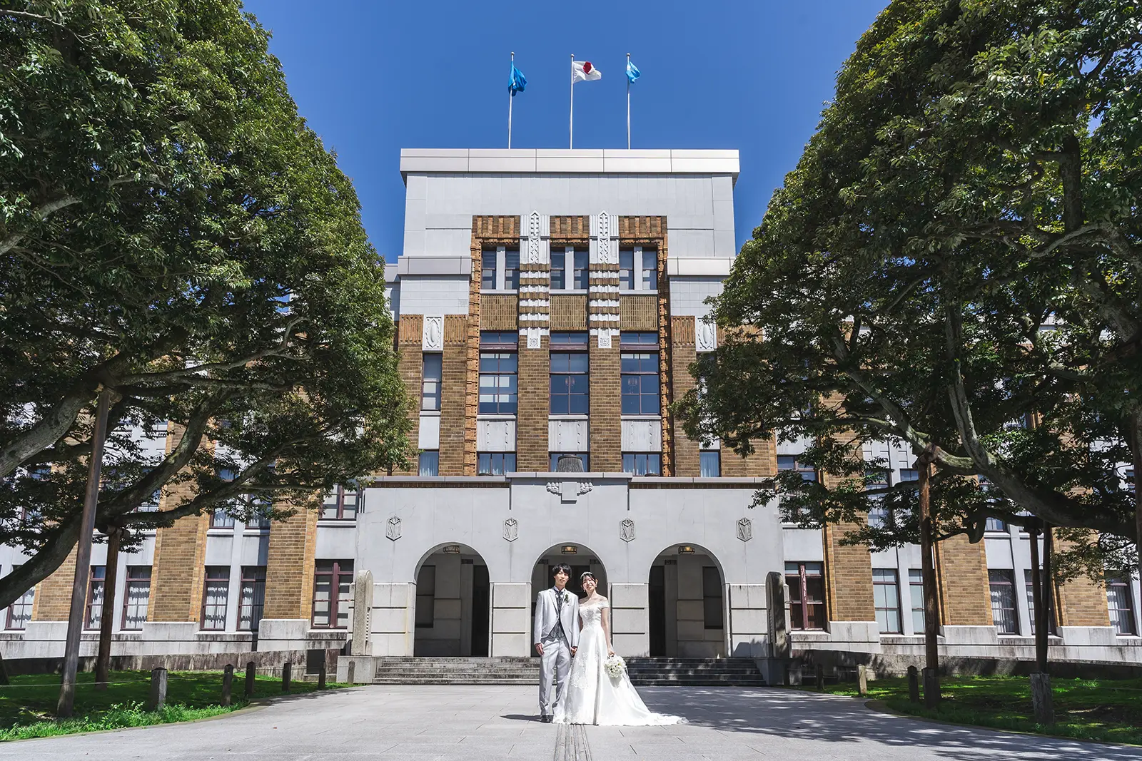 しいのき迎賓館の外観を背景にウェディングドレス姿の新郎新婦を撮影した写真