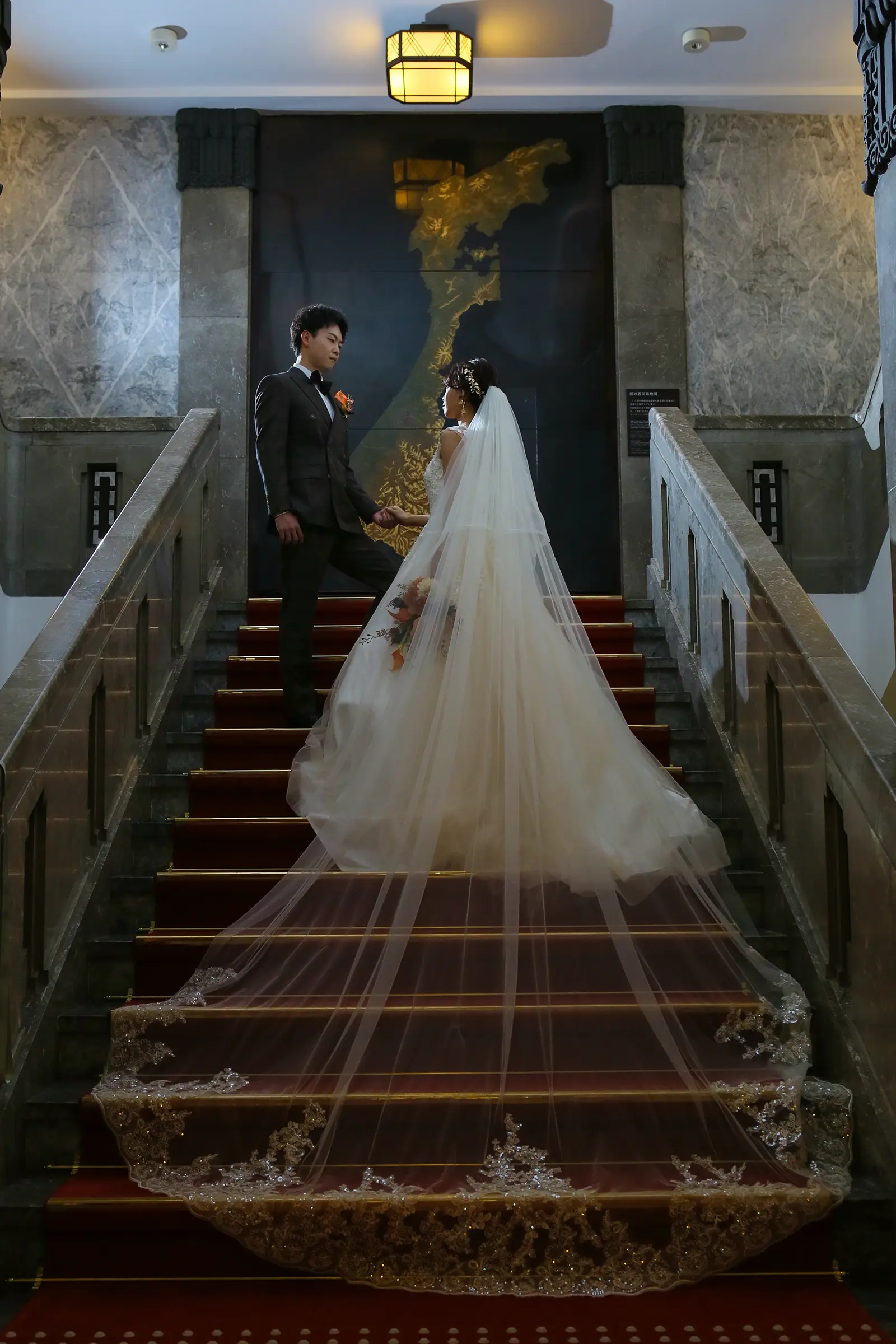 しいのき迎賓館の大階段でロングベールを広げた新郎新婦の洋装フォトウェディング写真