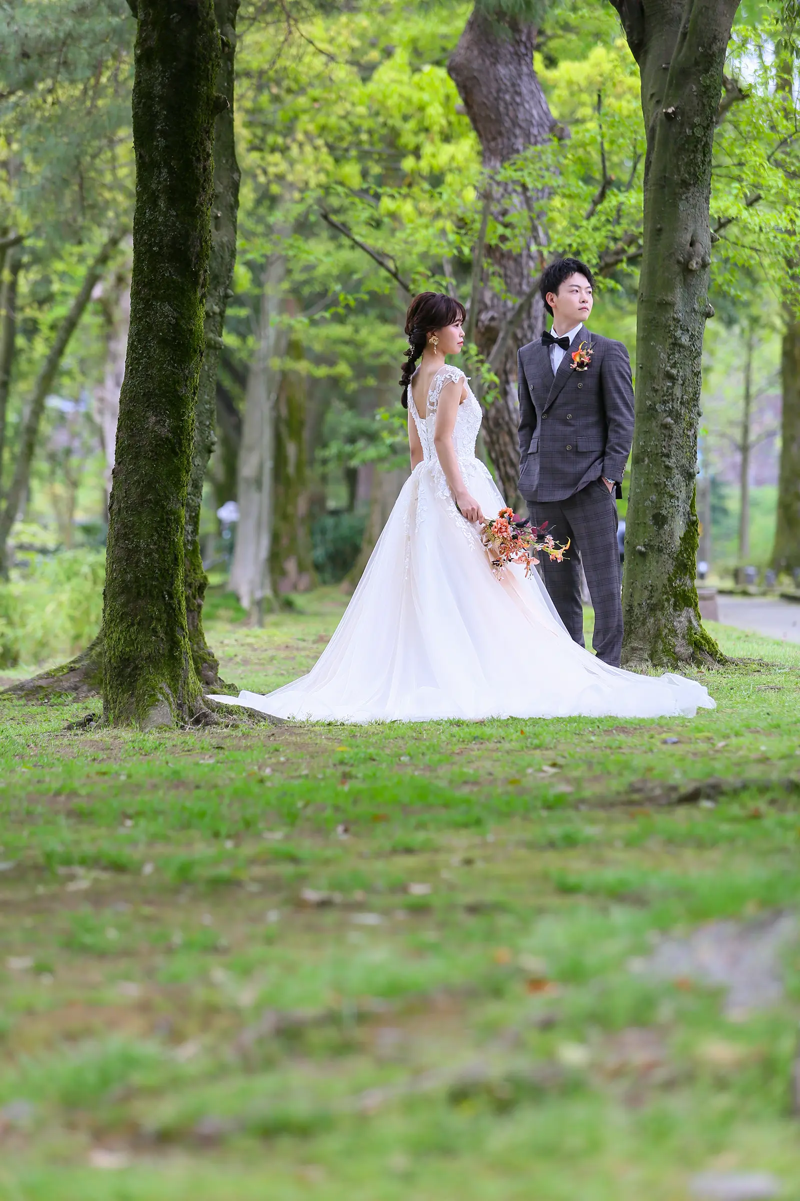 しいのき迎賓館周辺の緑の中でウェディングドレス姿の新郎新婦を撮影した写真