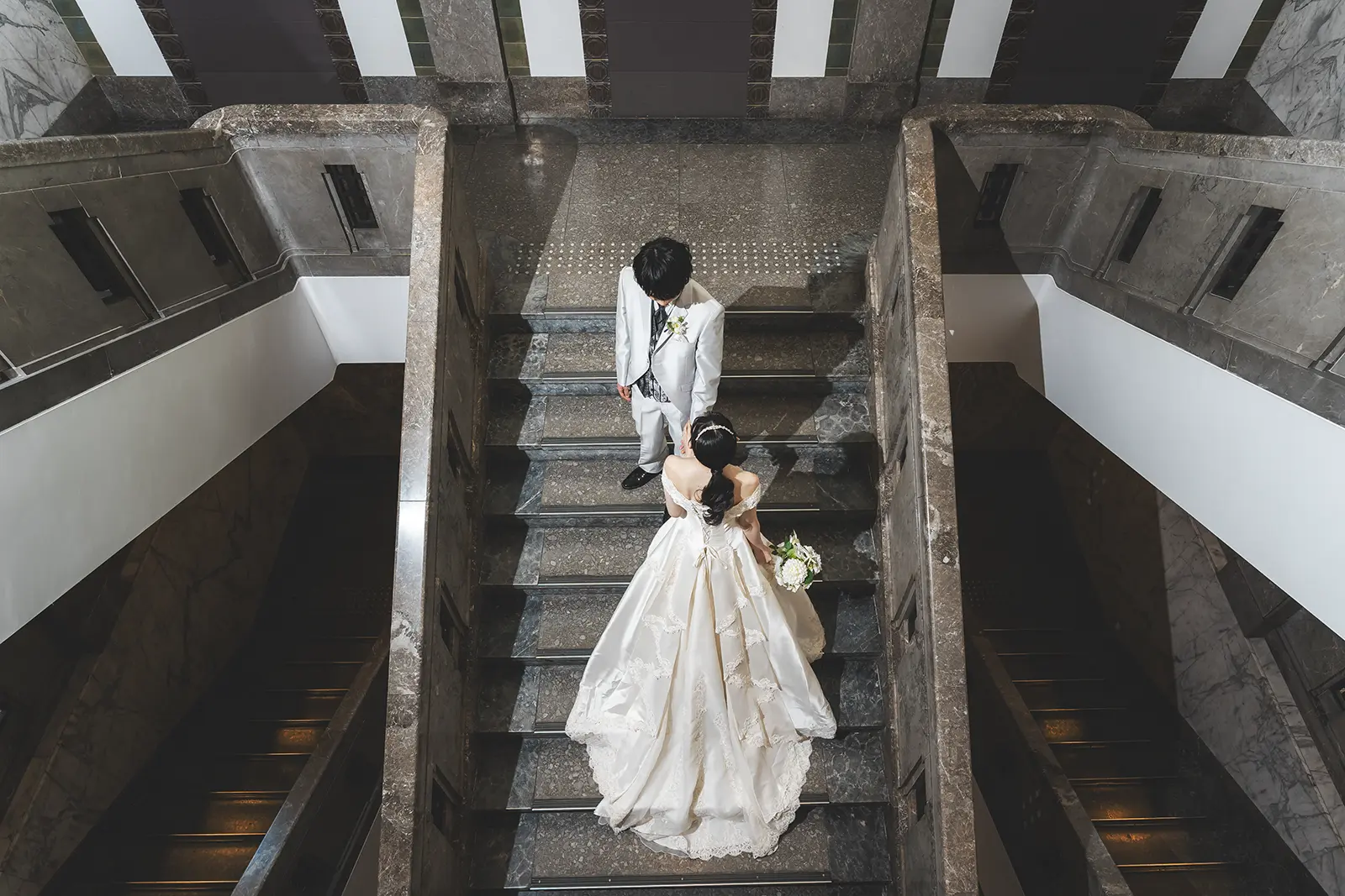しいのき迎賓館の階段を上から見下ろして撮影した新郎新婦の洋装フォトウェディング写真