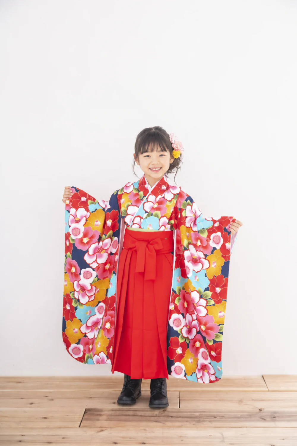 小学校卒業袴のスタジオ前撮り。椿柄の着物×赤袴で両袖を広げた一枚