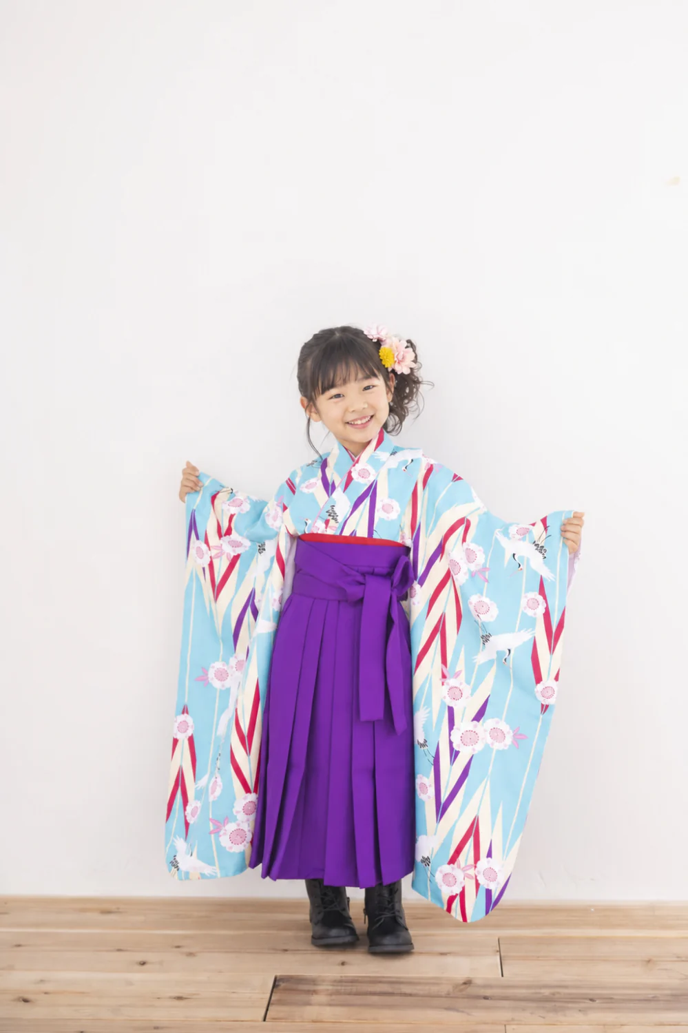 小学校卒業袴のスタジオ前撮り。水色の矢絣×紫袴で両袖を広げた全身カット