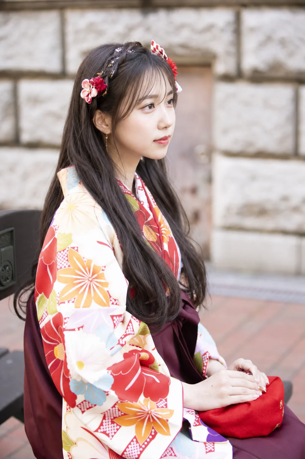 横浜のレンガと石壁を背景に、卒業袴姿で椅子に座る女性の前撮り写真