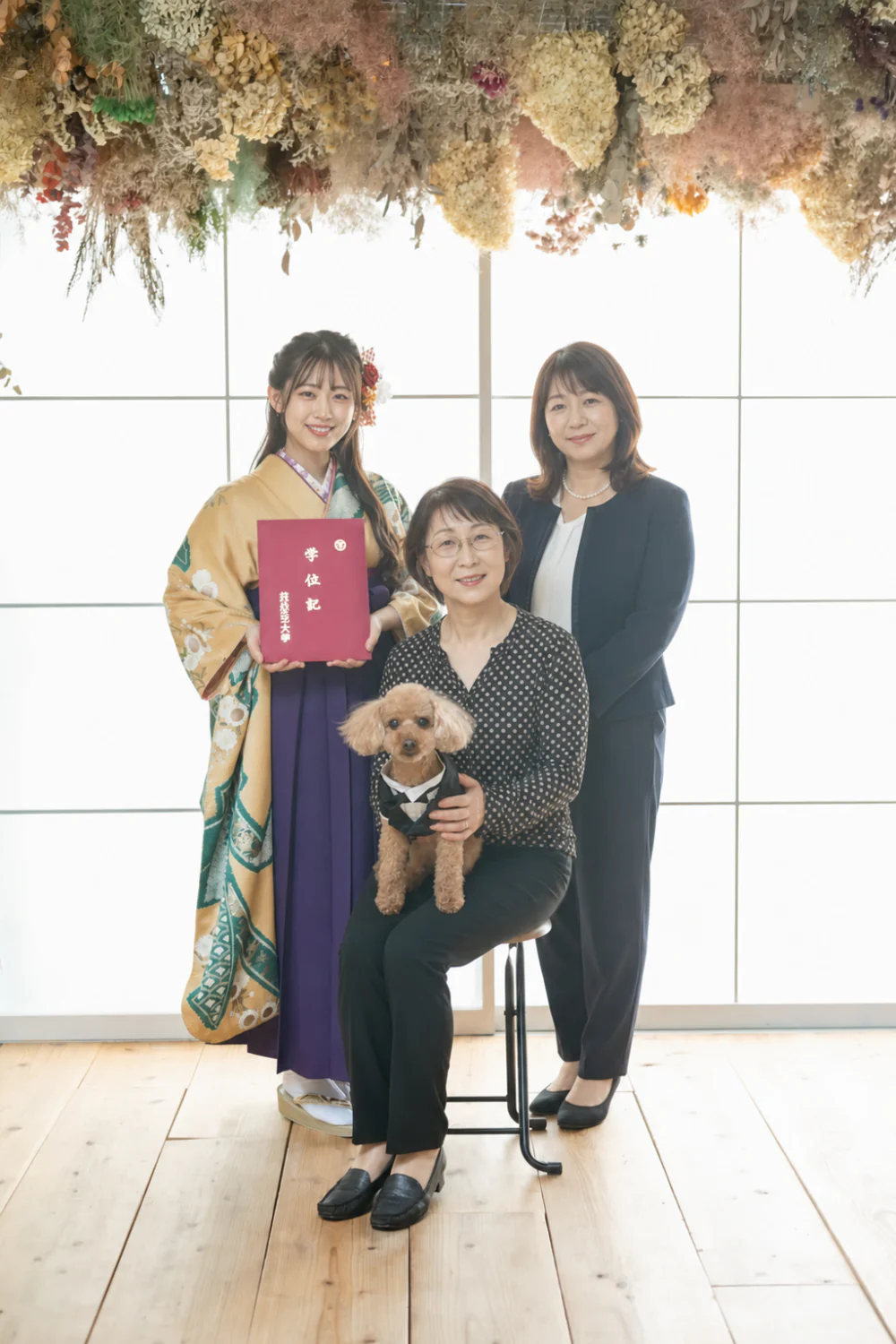 卒業袴姿の女性がご家族と愛犬と一緒に卒業証書を持って写るスタジオ前撮り写真