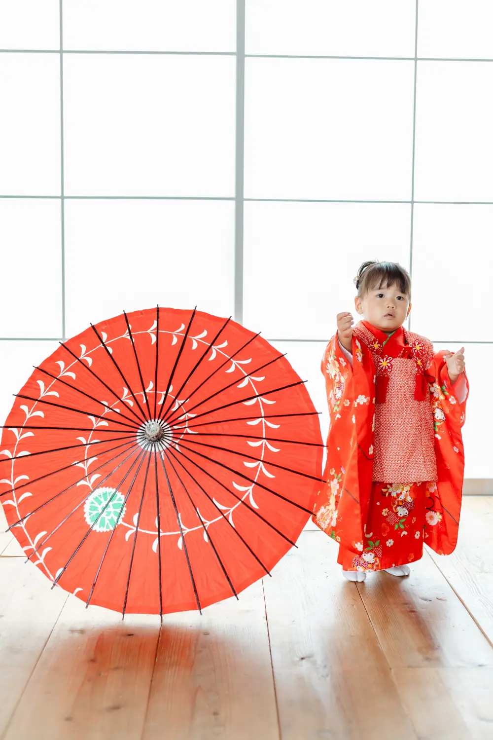 赤い和傘のそばに立つ被布姿の3歳の女の子、七五三スタジオ撮影（横浜）