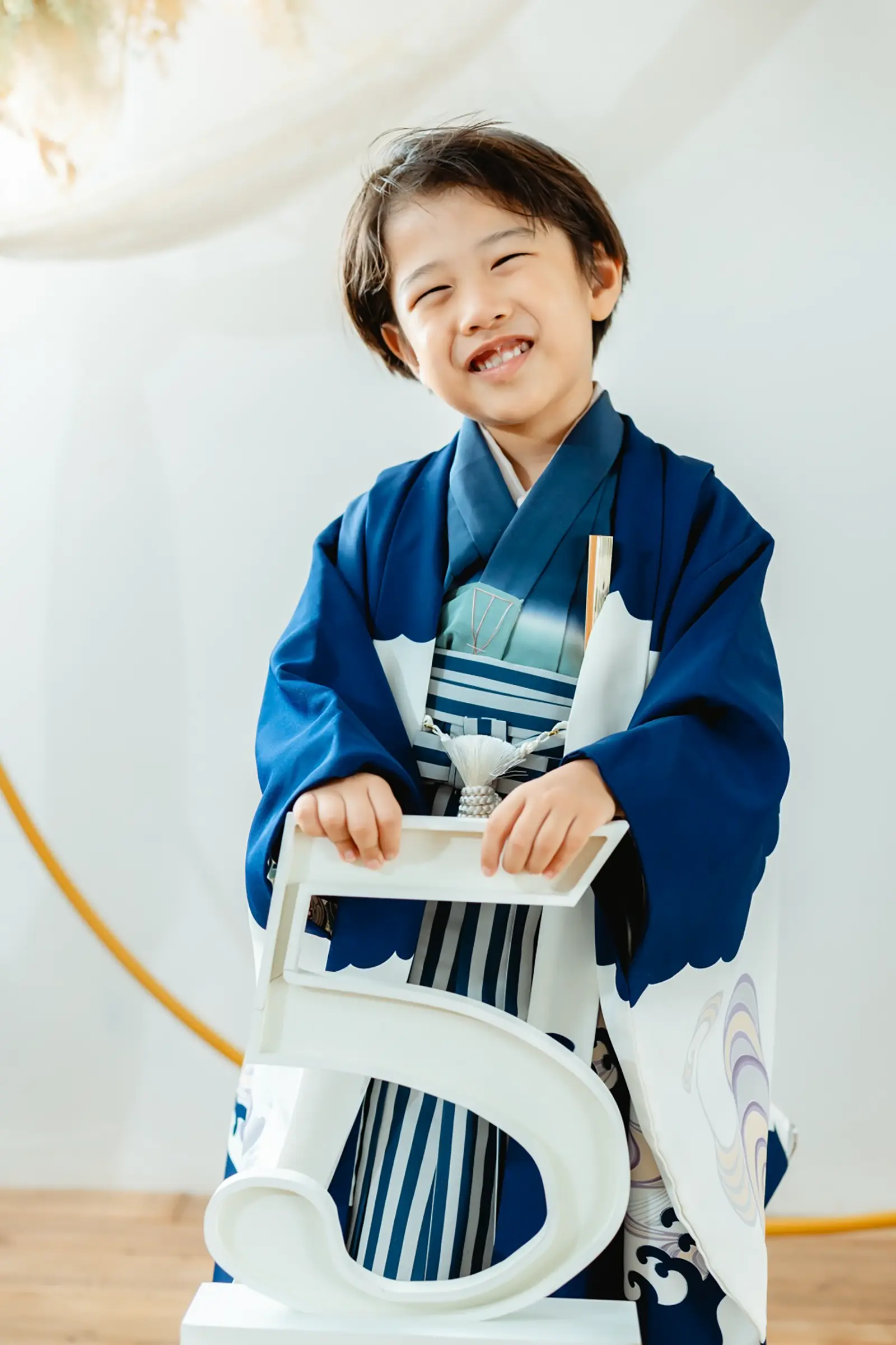数字の5のオブジェを抱えて笑う羽織袴姿の5歳の男の子、七五三スタジオ撮影（横浜）