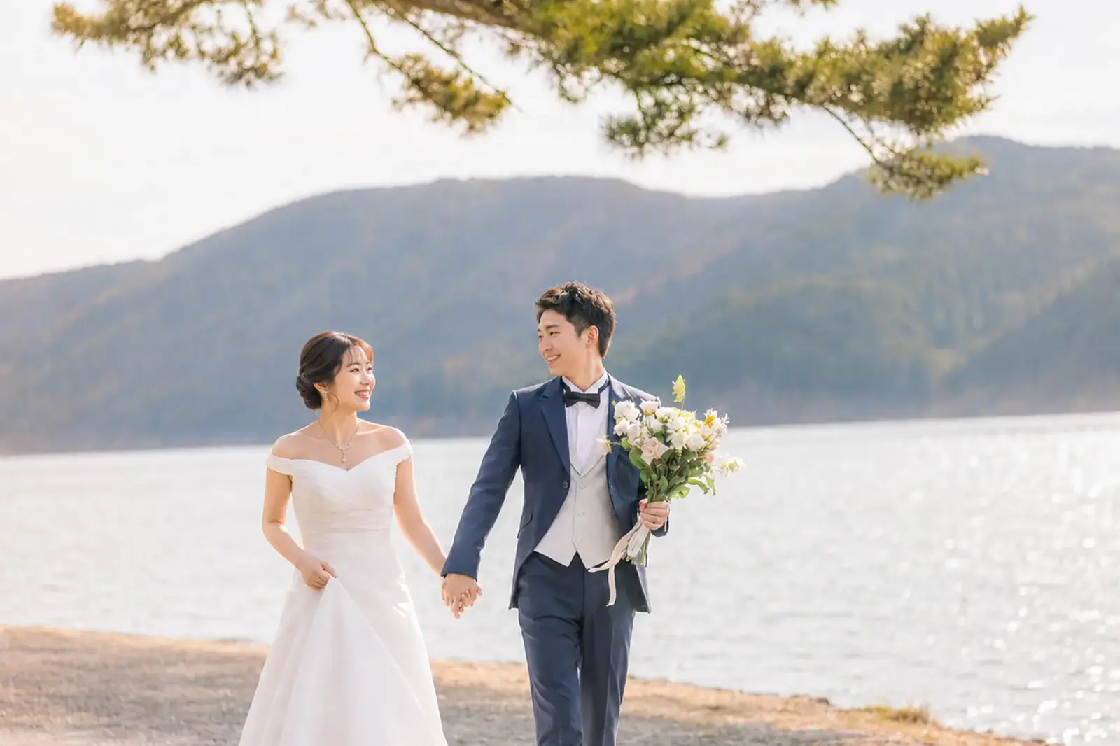 芦ノ湖畔を手をつないで歩く新郎新婦