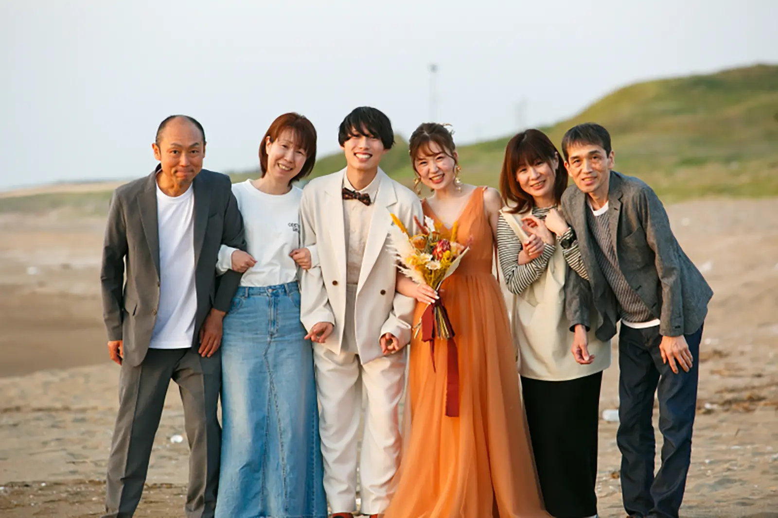 内灘マリーナ周辺の海辺で新郎新婦と家族が笑顔で並ぶフォトウェディング写真