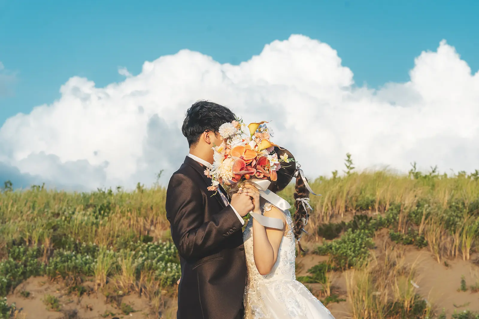 内灘マリーナ周辺の海辺で夕日を背景にウェディングドレス姿の新婦と新郎が立つ写真