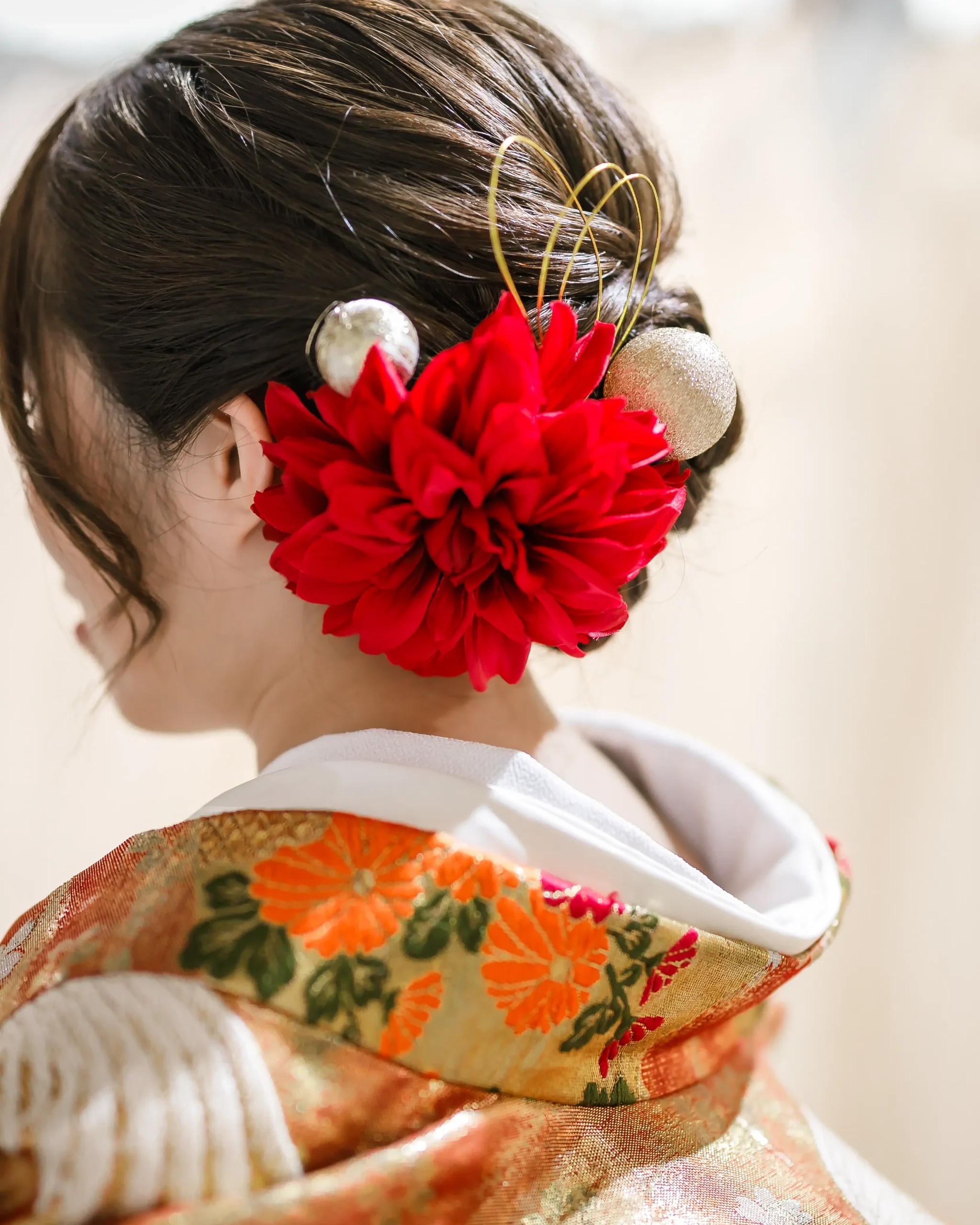 和装に合わせたピンクと白の花飾り、房飾り付きのヘアアレンジ
