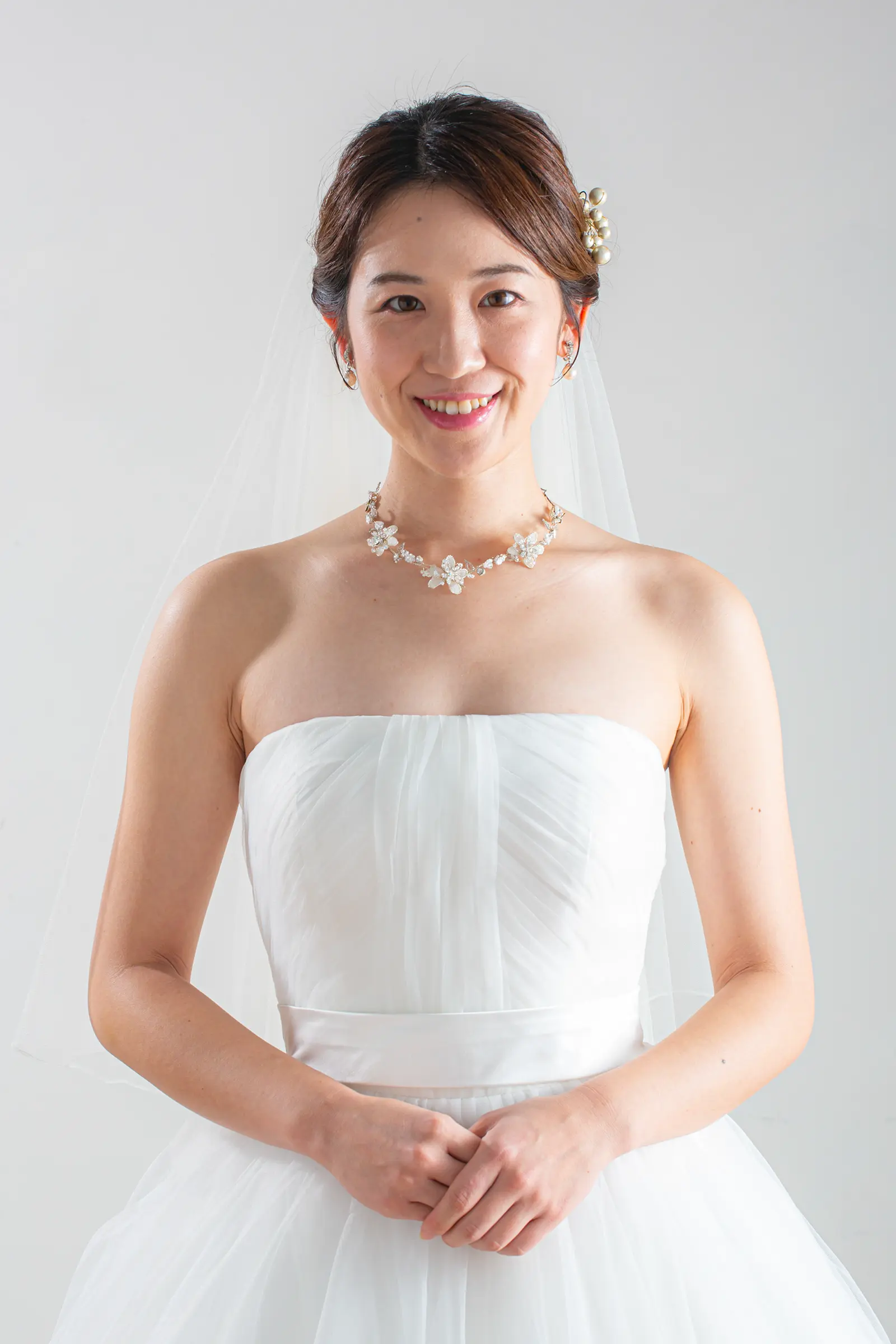繊細なチュール素材のロングベールを纏った花嫁の横顔アップ。ベールの透明感と、顔周りにあしらわれたレース柄が美しく際立つ一枚。