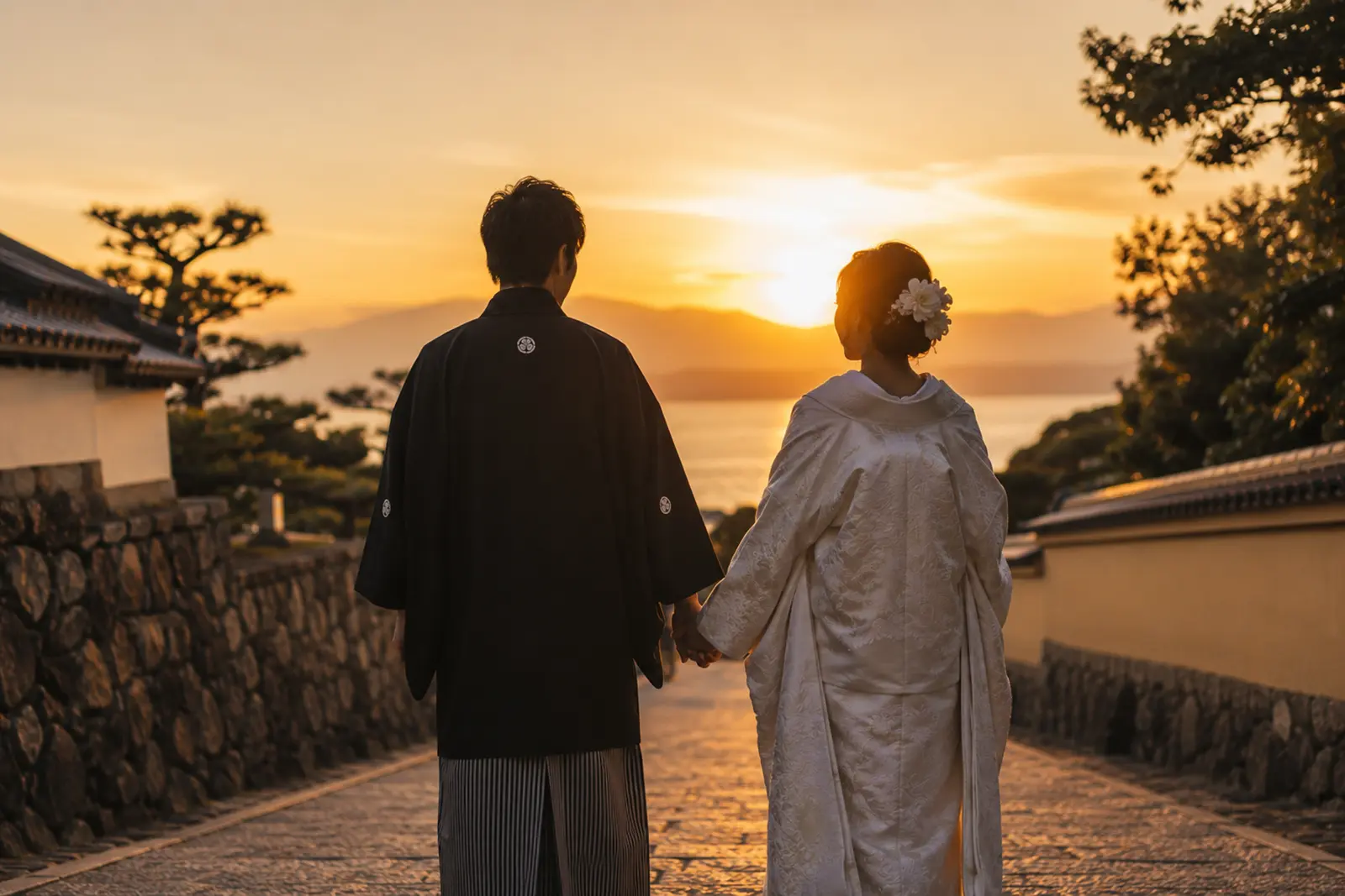 夕暮れの道で手をつなぐ新郎新婦の後ろ姿