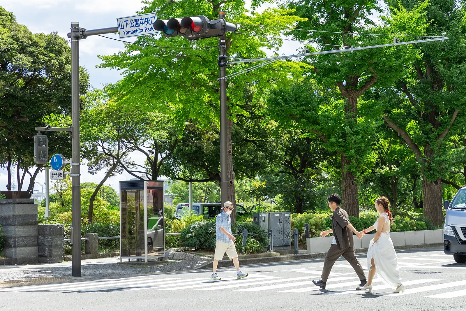 山下公園前の横断歩道を歩く洋装前撮りの新郎新婦