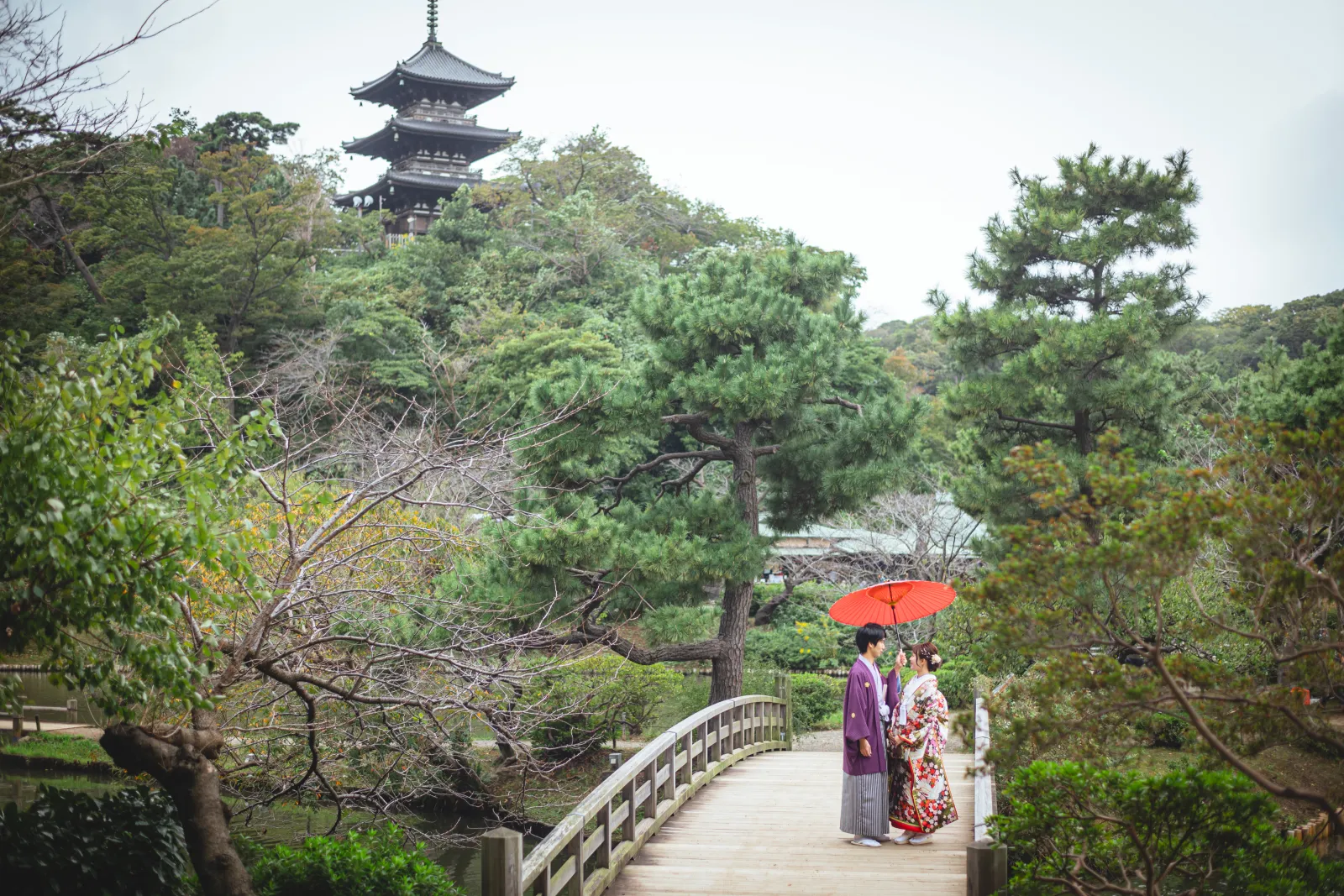 横浜の日本庭園の橋の上で見つめ合う新郎新婦、三重塔を背景にした和装ロケーションフォト