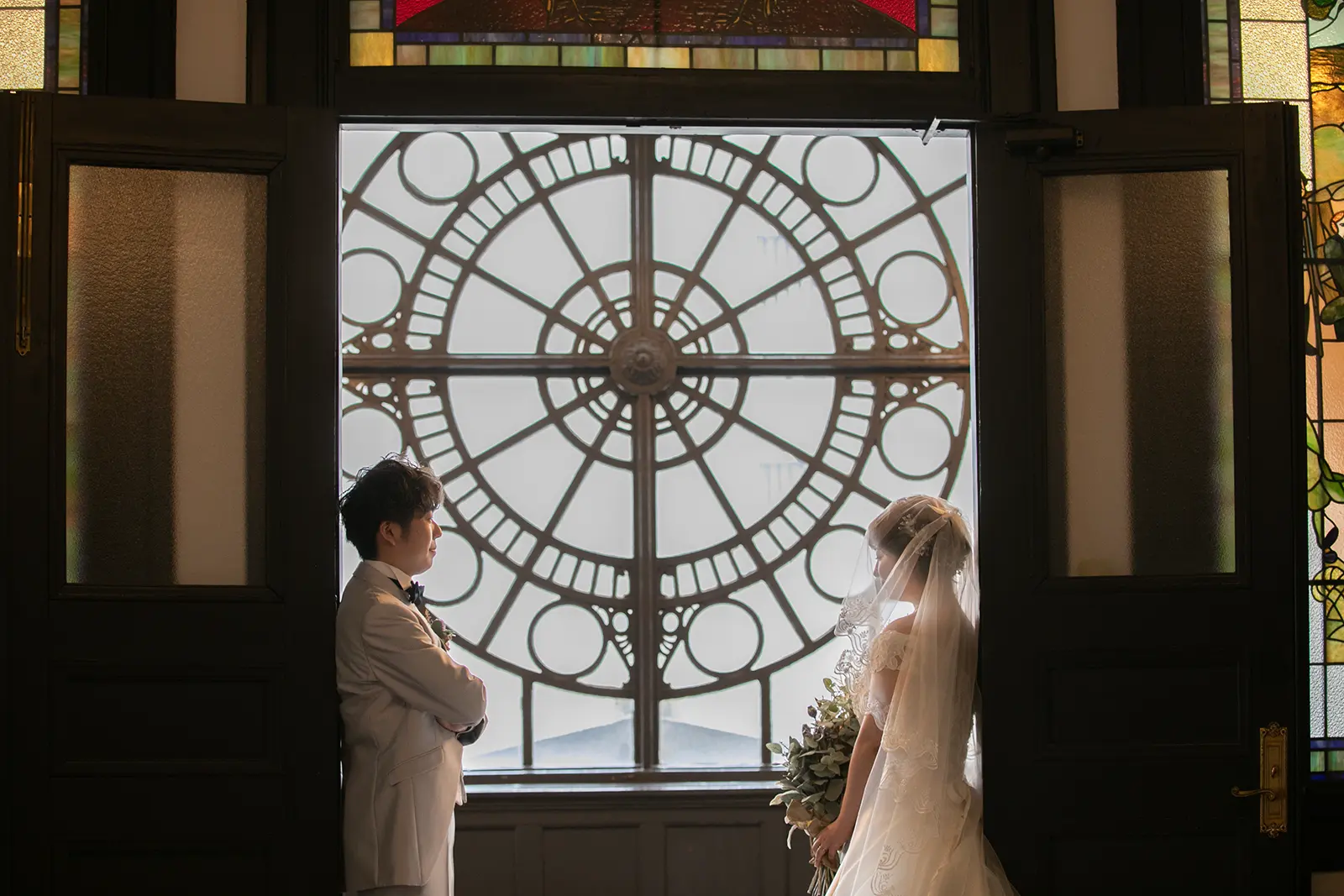横浜市開港記念会館の時計窓を背景に向かい合う新郎新婦