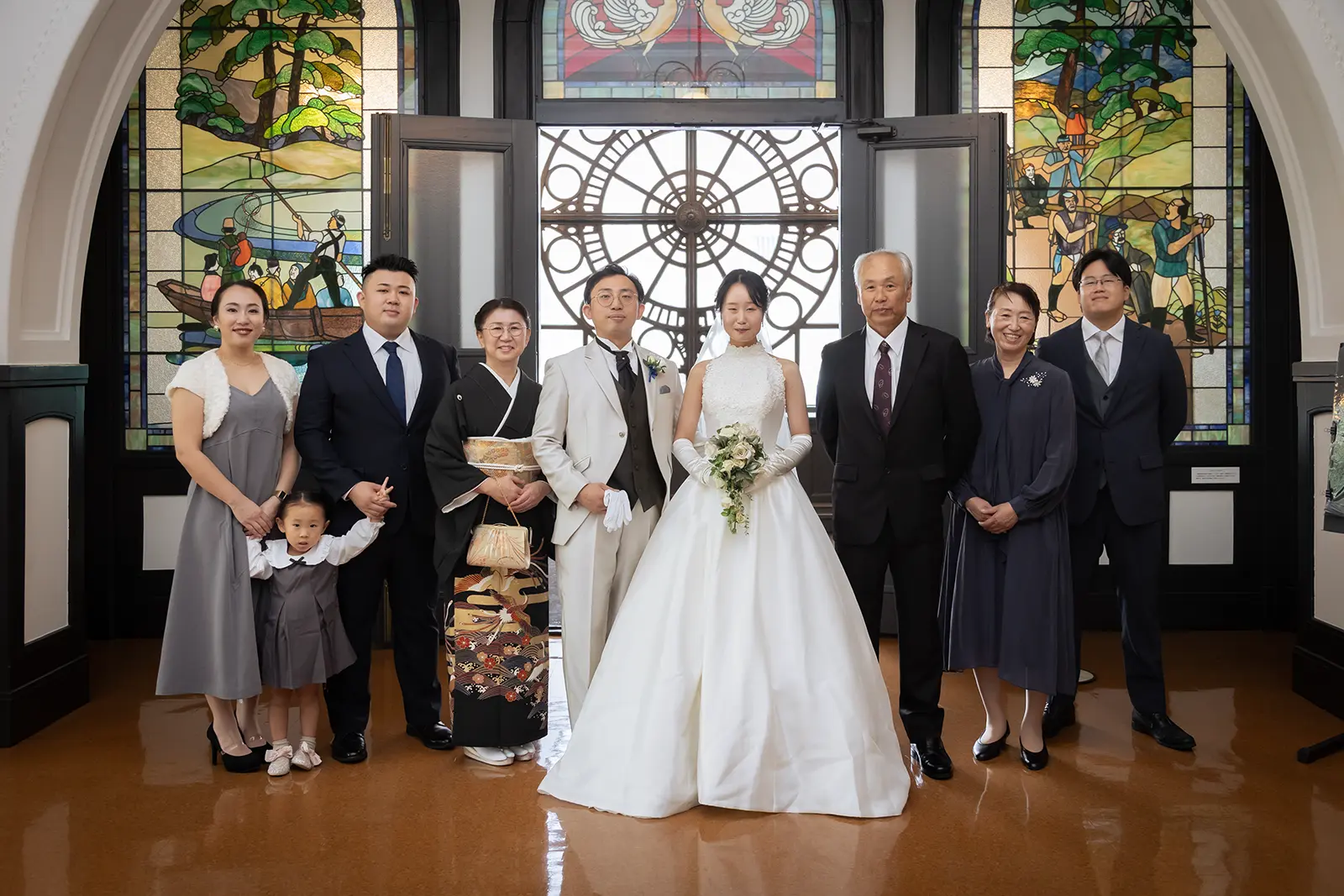 横浜市開港記念会館のステンドグラス前で撮影する新郎新婦と家族の集合写真
