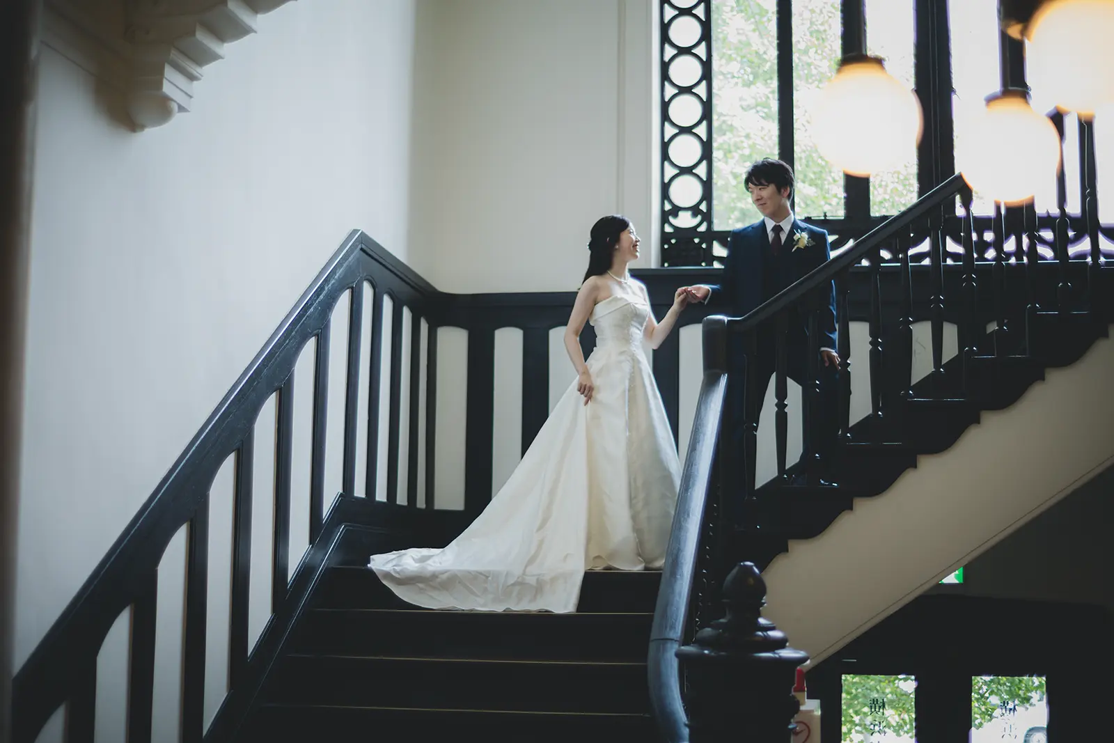 横浜市開港記念会館の階段で手を取り合う洋装の新郎新婦