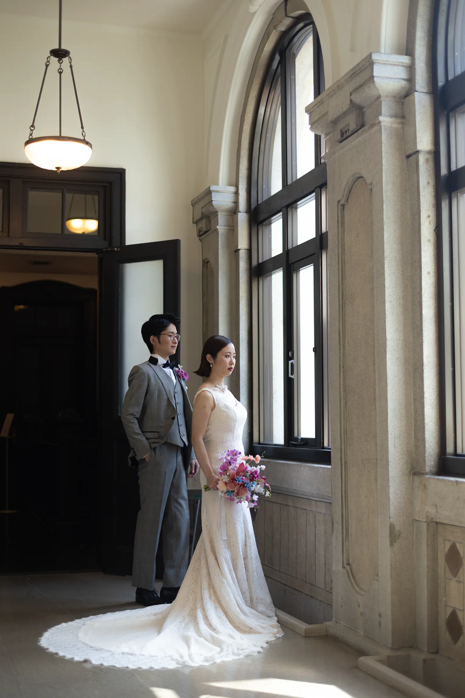 横浜市開港記念会館の窓辺に立つ洋装の新郎新婦