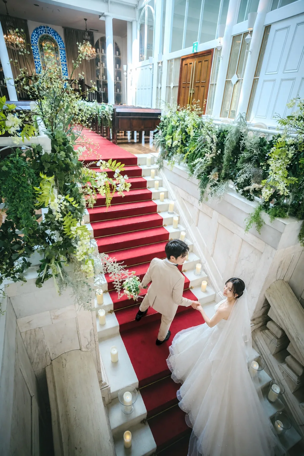 ラ・バンク・ド・ロアの大階段を上から見下ろした縦構図。装花と赤い絨毯、新郎新婦