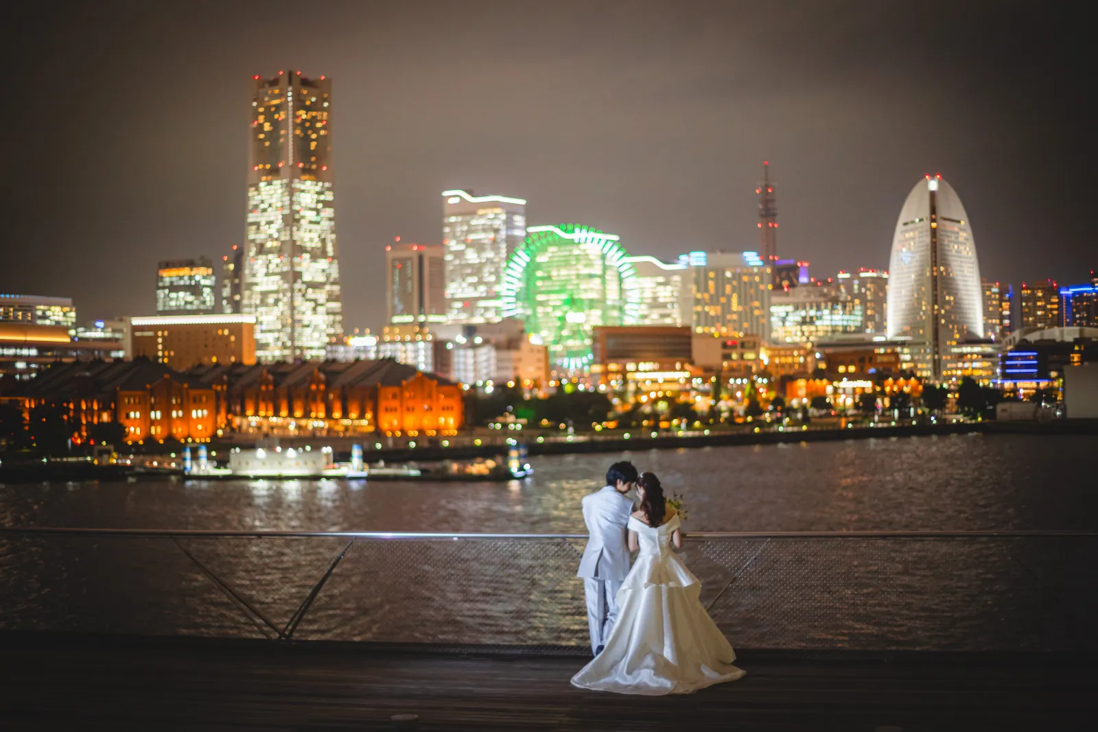 横浜・みなとみらいの夜景を背景に寄り添う新郎新婦、洋装ウェディングドレスのロケーションフォト