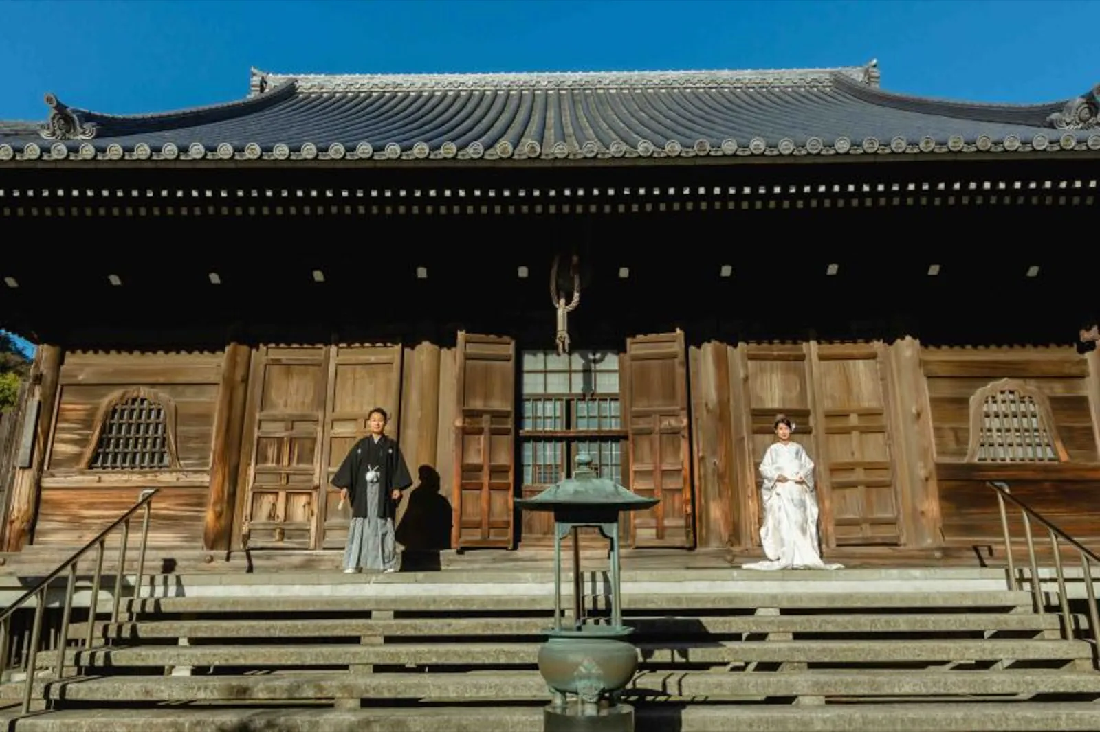 歴史を感じる称名寺の建物を背景に凛と立つ白無垢と黒紋付の新郎新婦｜和装ロケーション