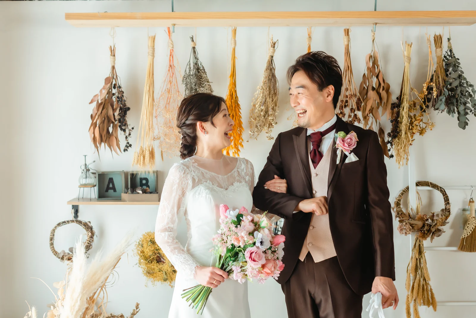 スタジオでリラックスして笑い合う洋装の新郎新婦