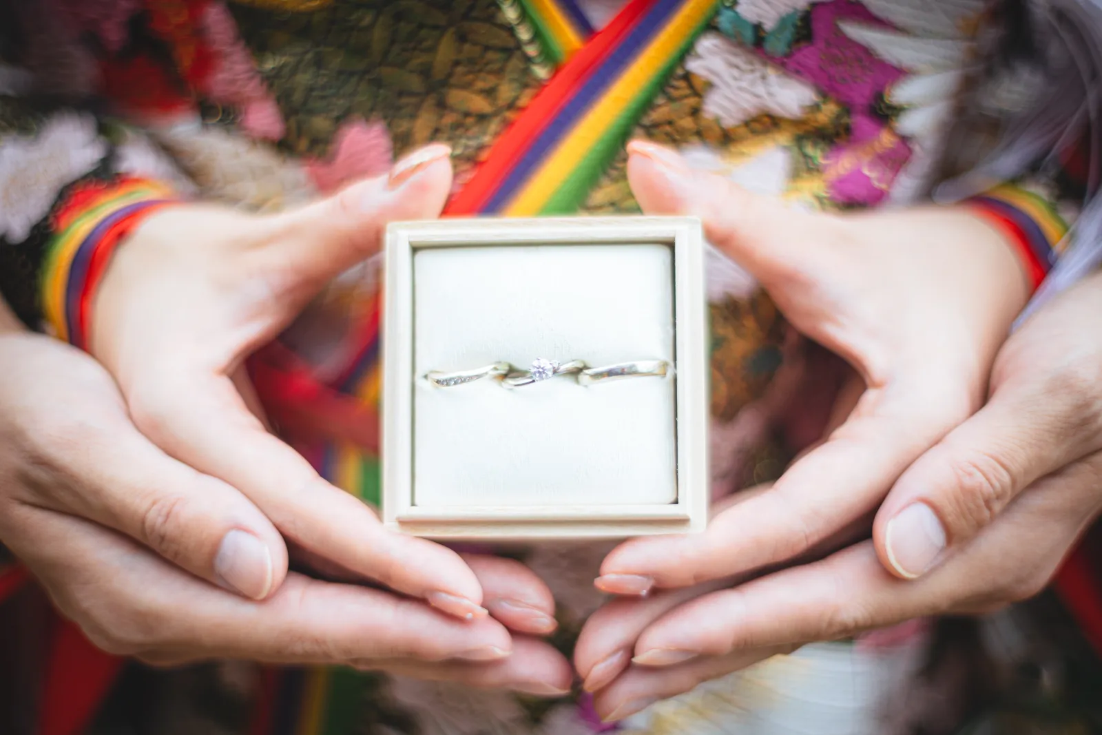 色打掛の帯の前で結婚指輪を手に持つクローズアップカット
