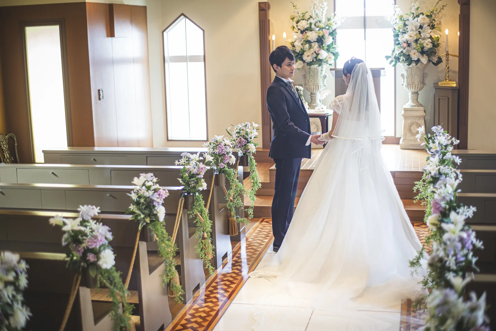 祭壇前で花に囲まれて向かい合う新郎新婦