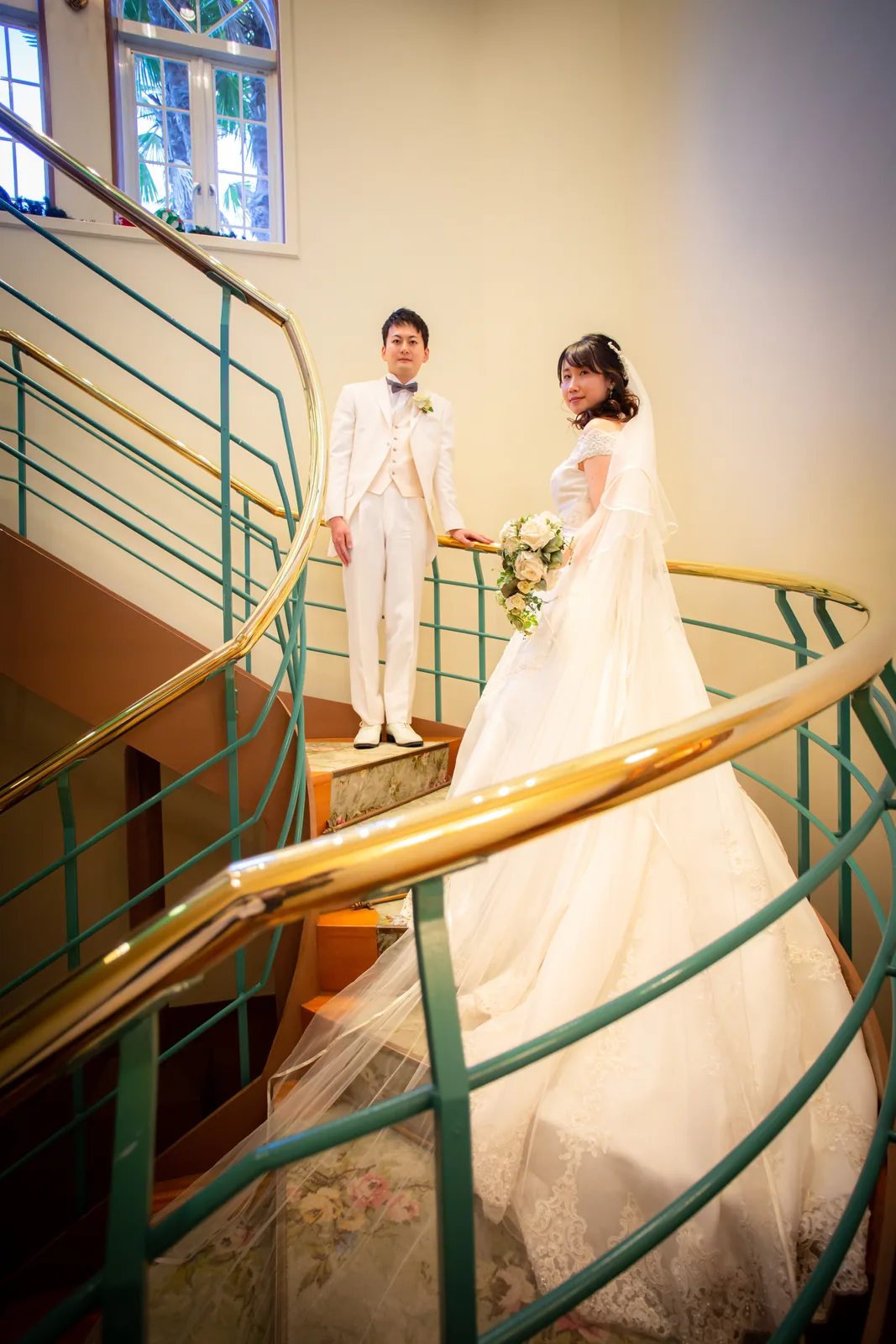 らせん階段を降りてくる新郎新婦を下から見上げたカット