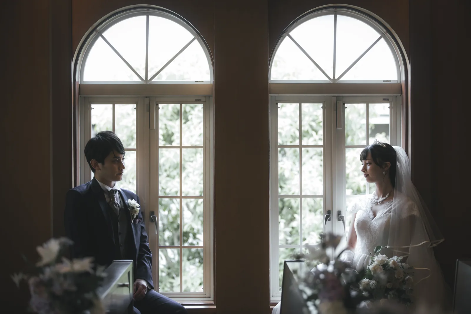 アーチ窓を背に見つめ合う新郎新婦のクラシカルなウエディングフォト