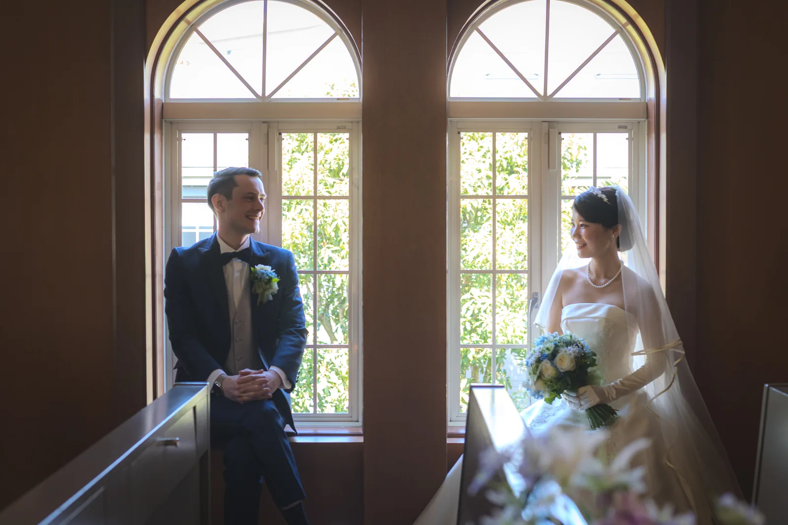 二連のアーチ窓の前に立つ新郎新婦を引きで撮影したフォトウェディング