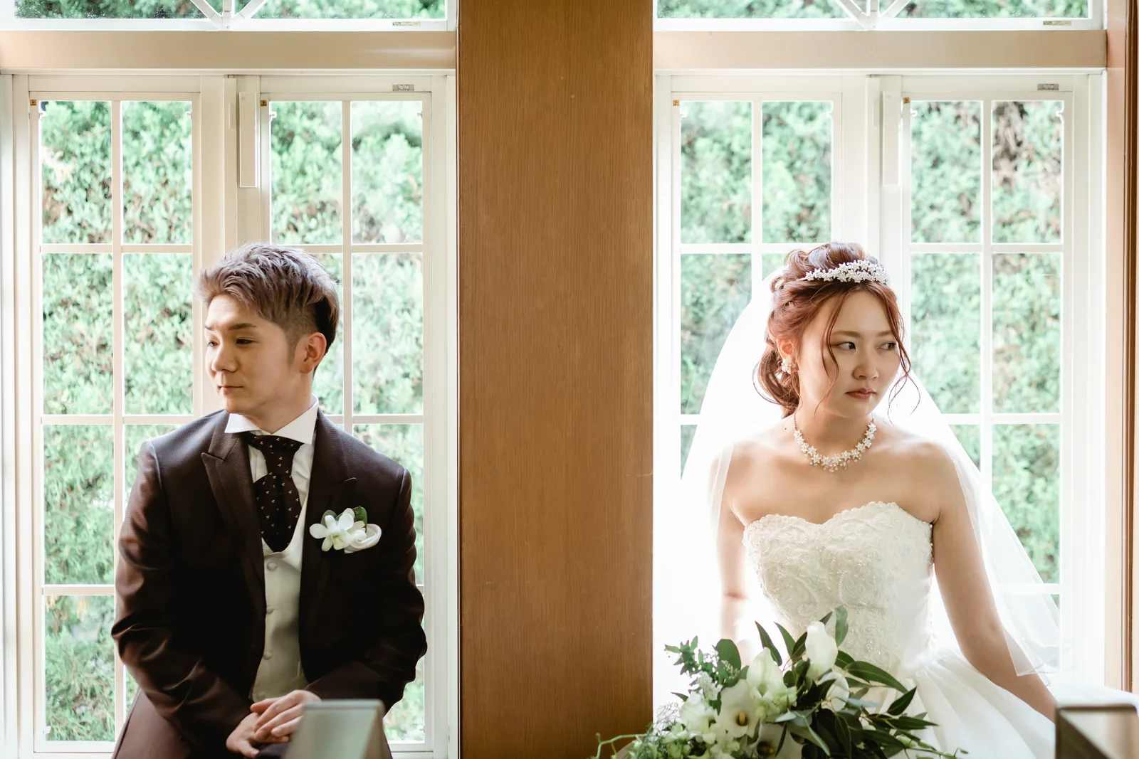それぞれの窓辺に立つ新郎と新婦を並べて撮影したウエディングフォト