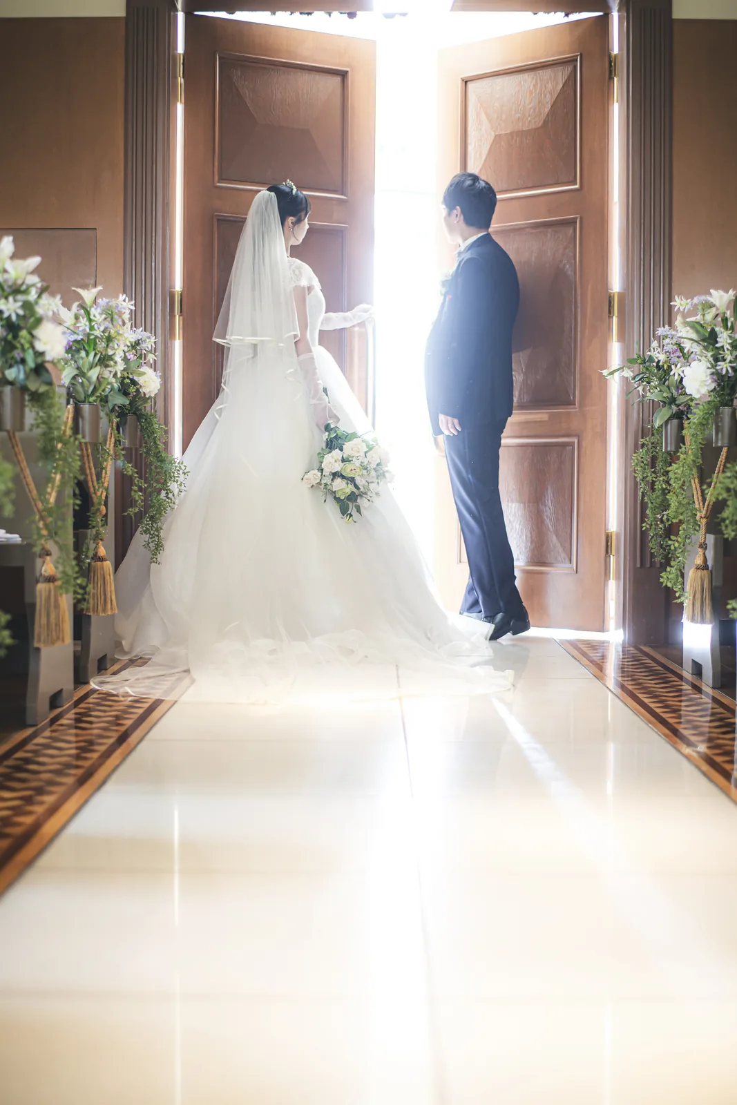 扉から差し込む逆光のなかに立つウエディングドレス姿の花嫁