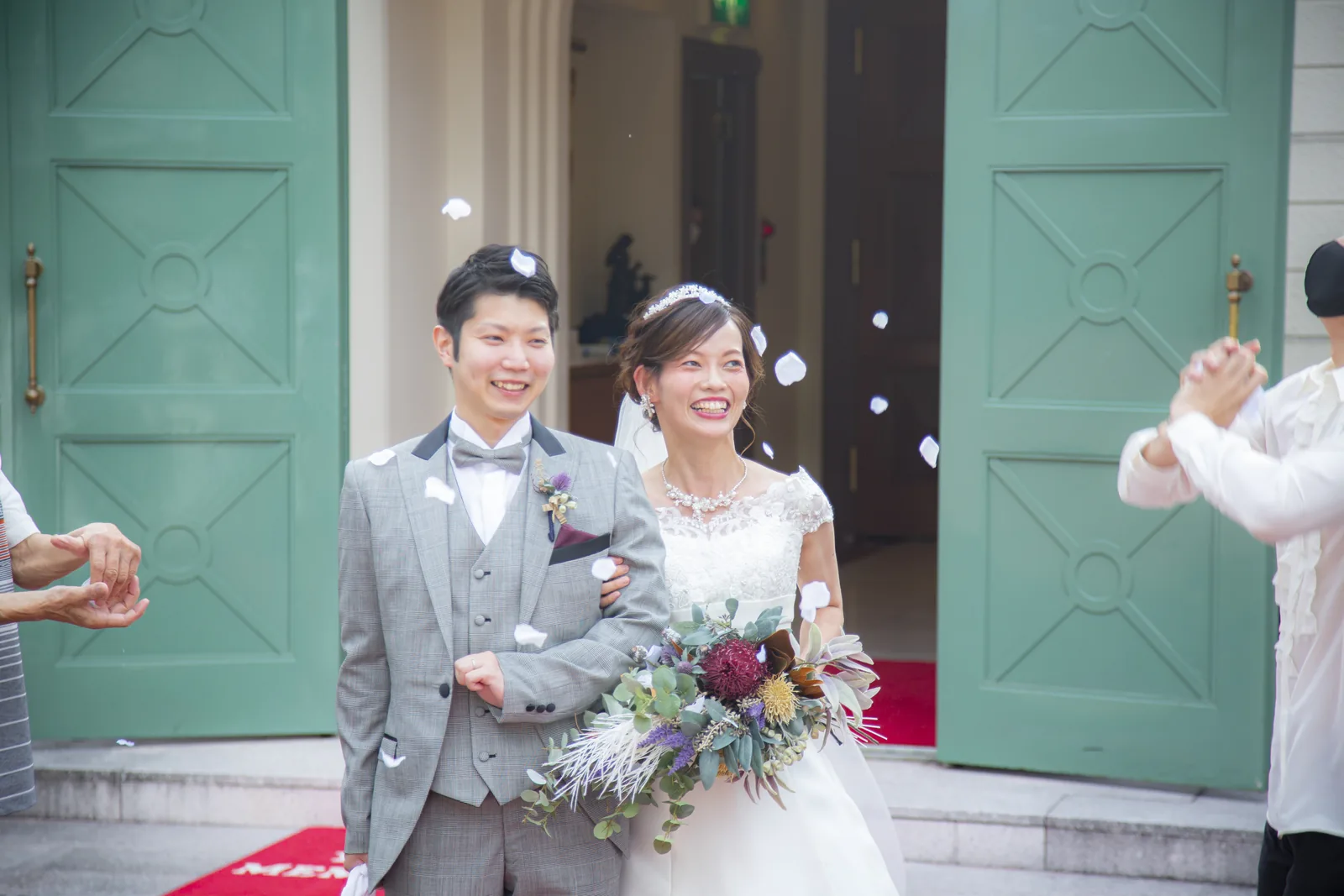 グリーンの扉の前でフラワーシャワーを受ける新郎新婦