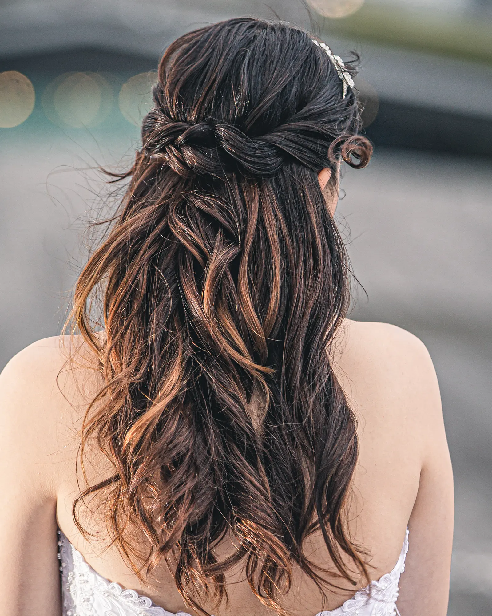 洋装のロングヘアをゆるく巻き、後ろでまとめたハーフアップの花嫁ヘアスタイル