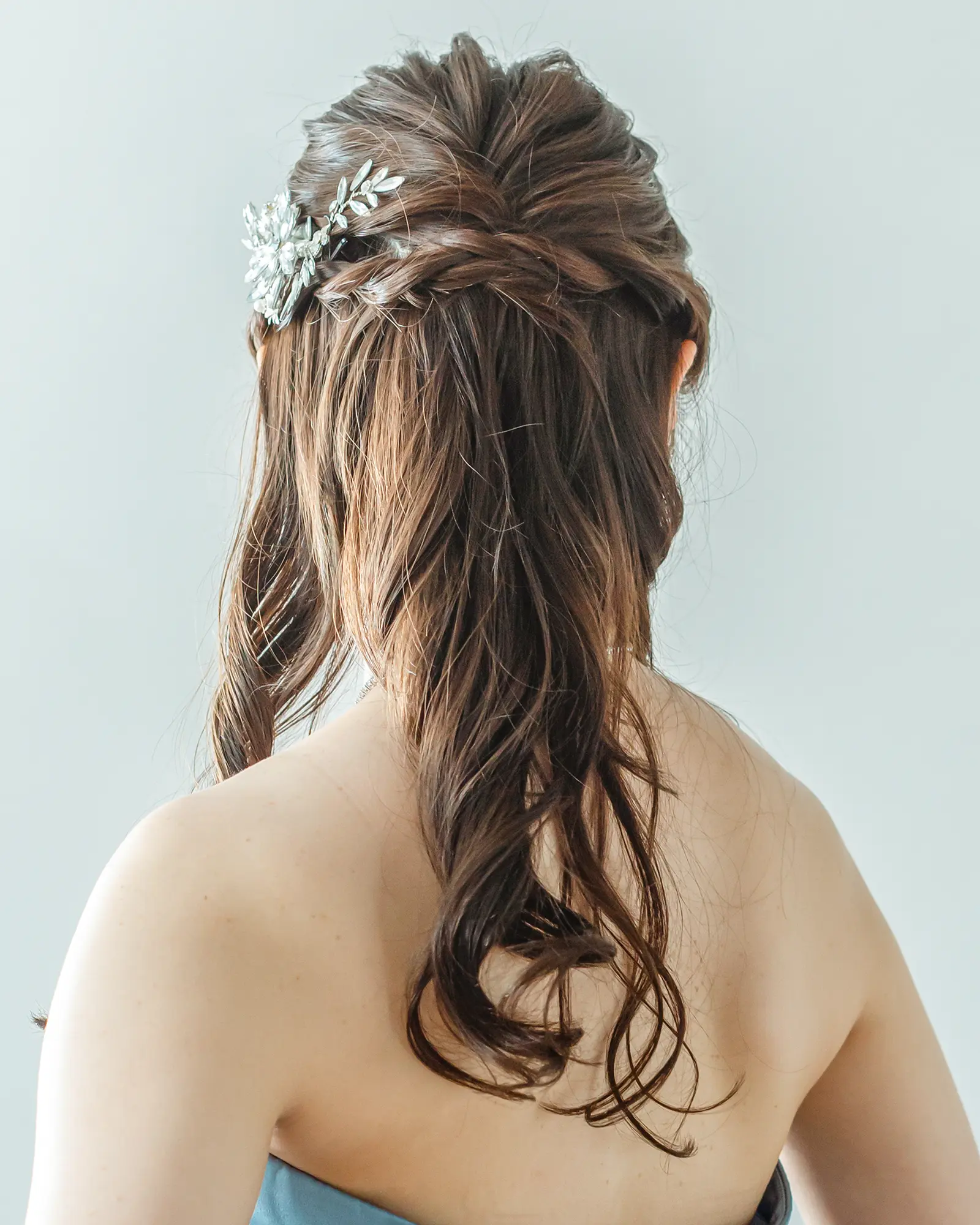 洋装のロングヘアを自然にまとめ、アクセサリーを添えたナチュラルなハーフアップの花嫁ヘアスタイル