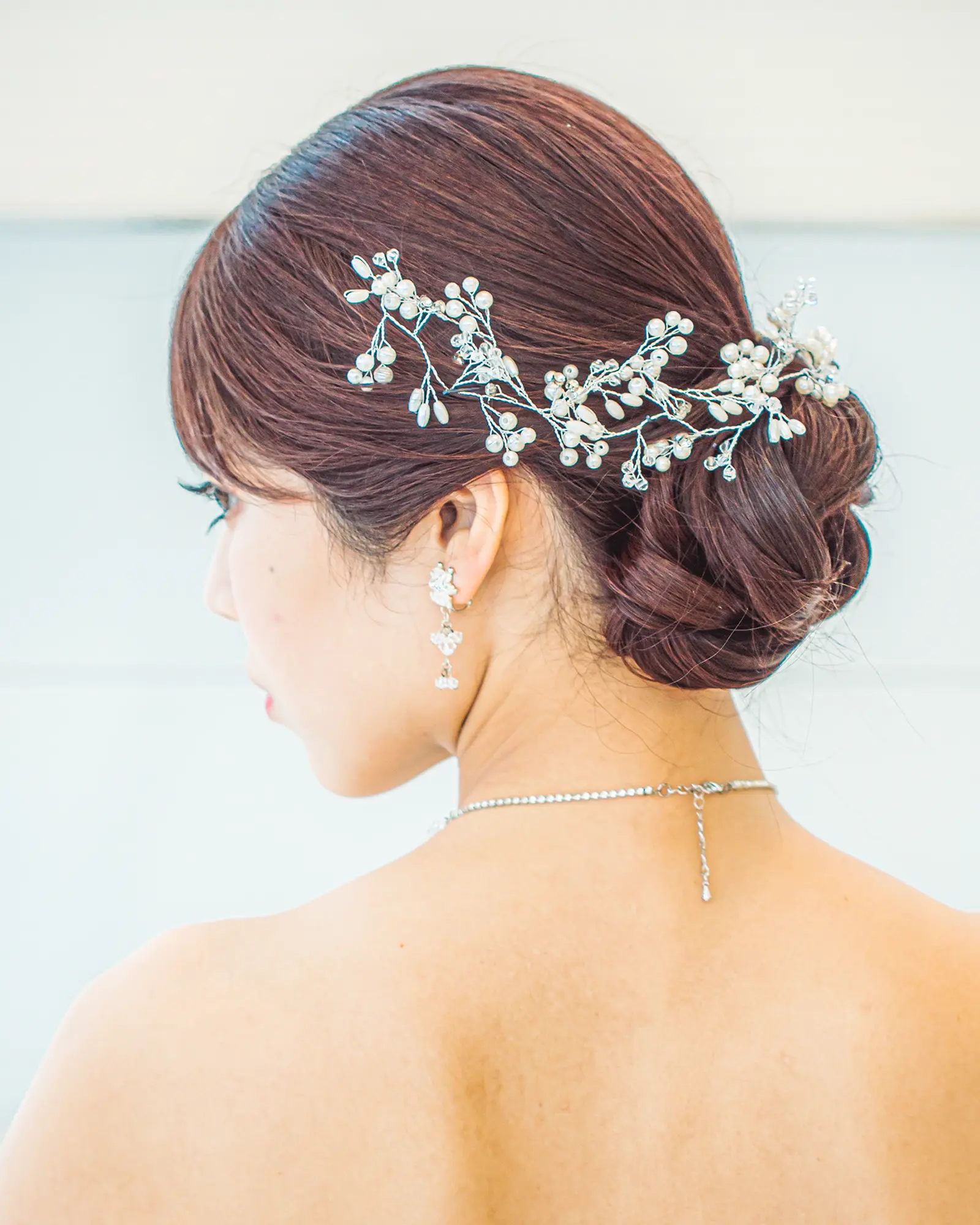 洋装のロングヘアを低めのシニヨンにまとめ、アクセサリーを合わせた花嫁ヘアスタイル