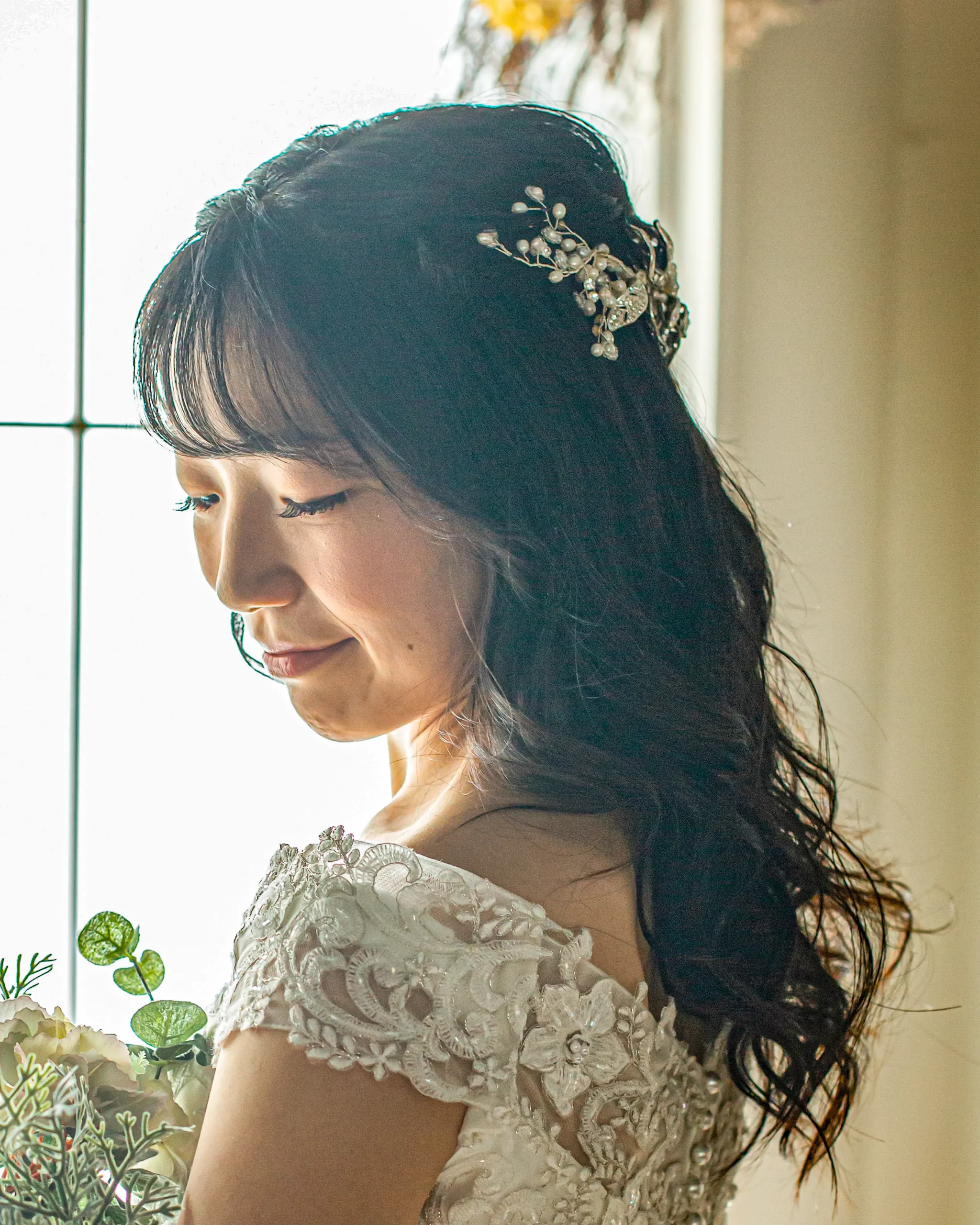 洋装のロングヘアを片側に流し、アクセサリーを添えたダウンスタイルの花嫁ヘア