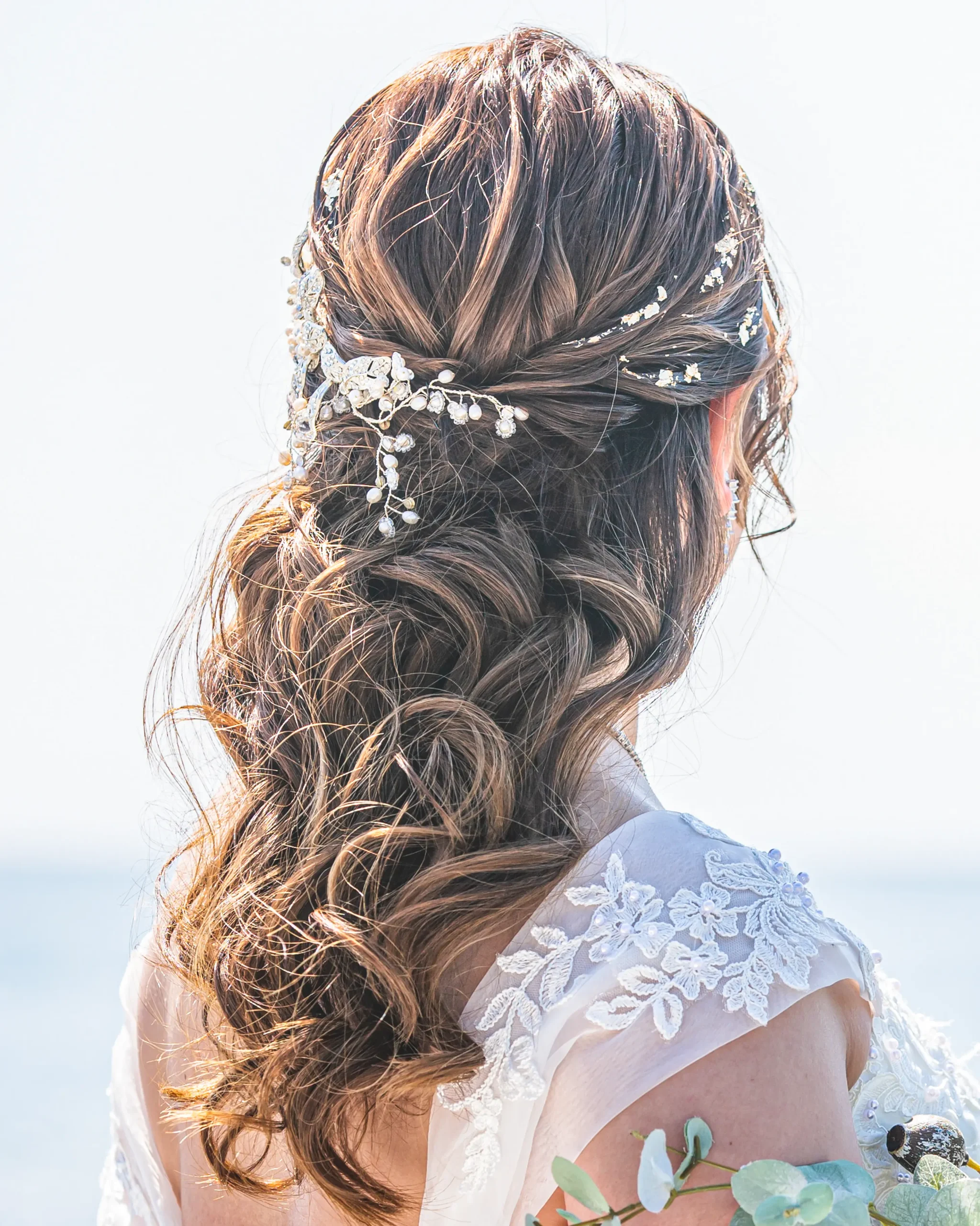 洋装のロングヘアを巻いてハーフアップにし、ビジューアクセサリーを合わせた花嫁ヘアスタイル