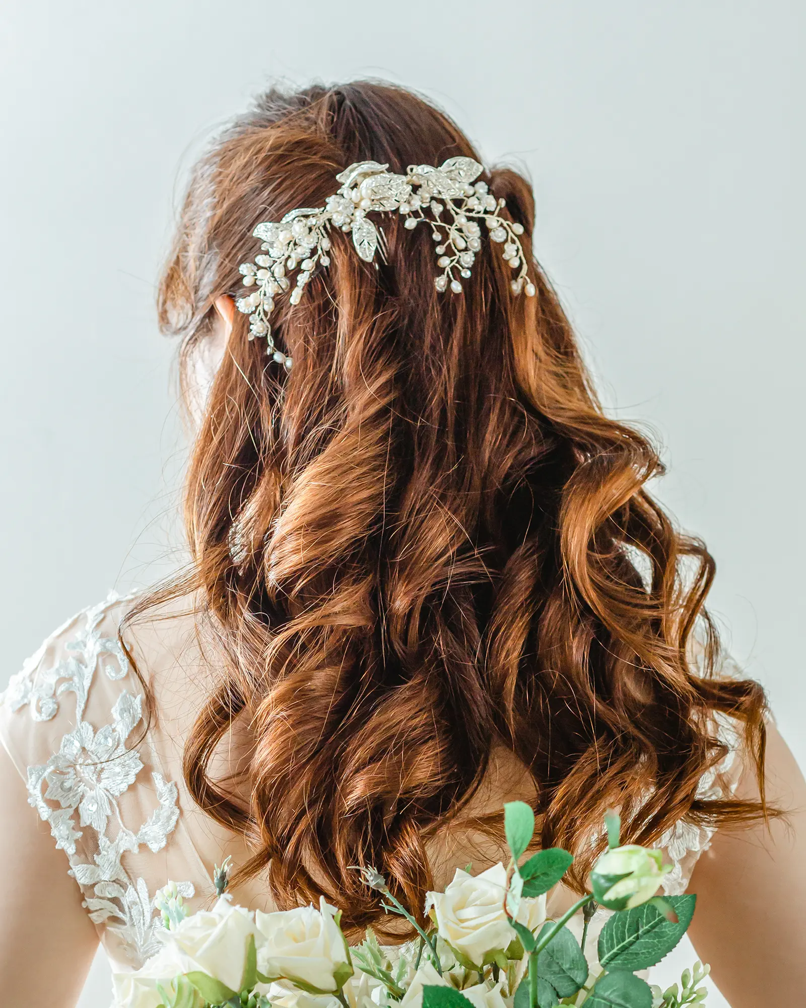 洋装のロングヘアをゆるく巻き、ビジューアクセサリーを合わせたハーフアップの花嫁ヘアスタイル