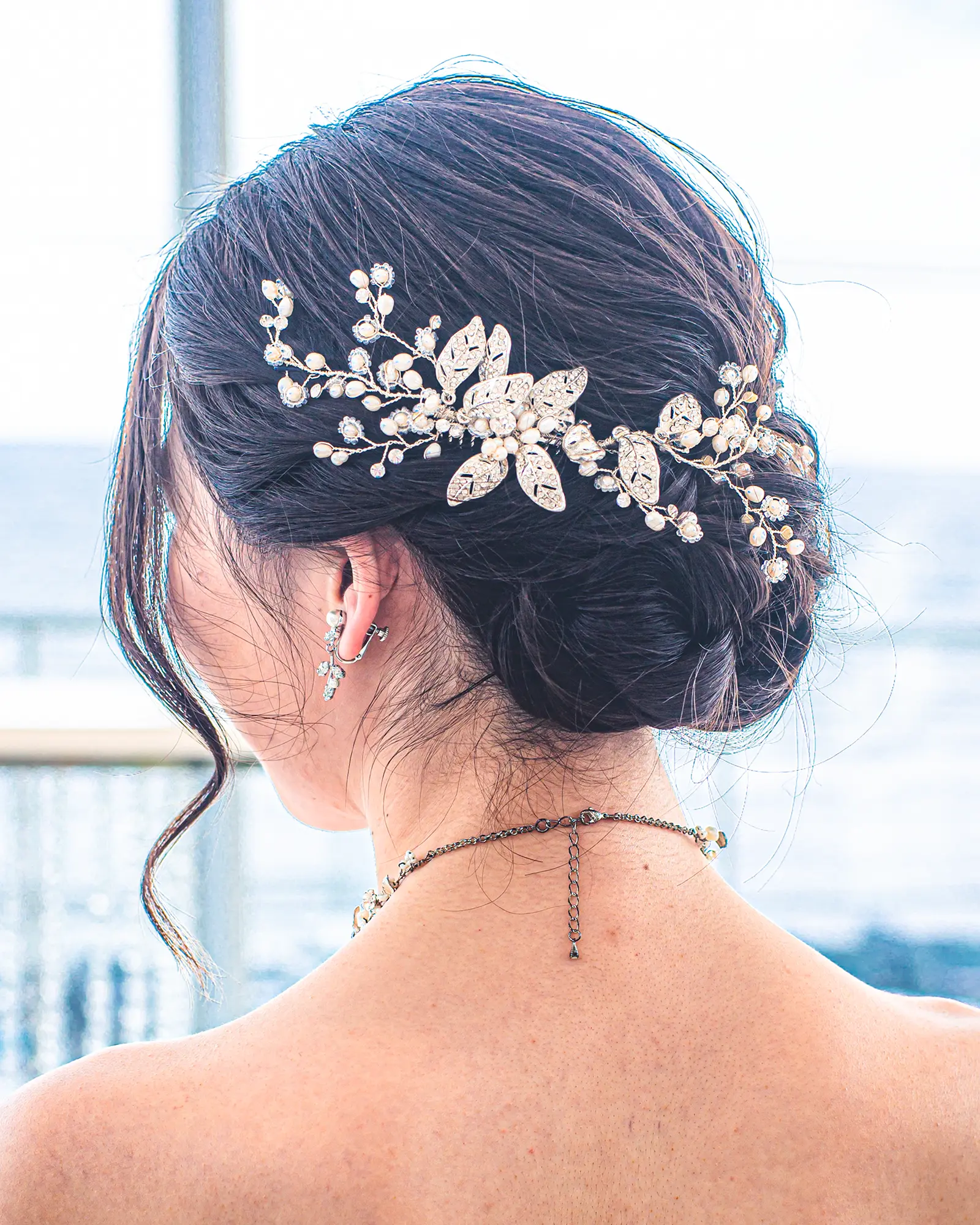 洋装のセミロングヘアを低めのシニヨンにまとめ、ゴールドアクセサリーを合わせた花嫁ヘアスタイル